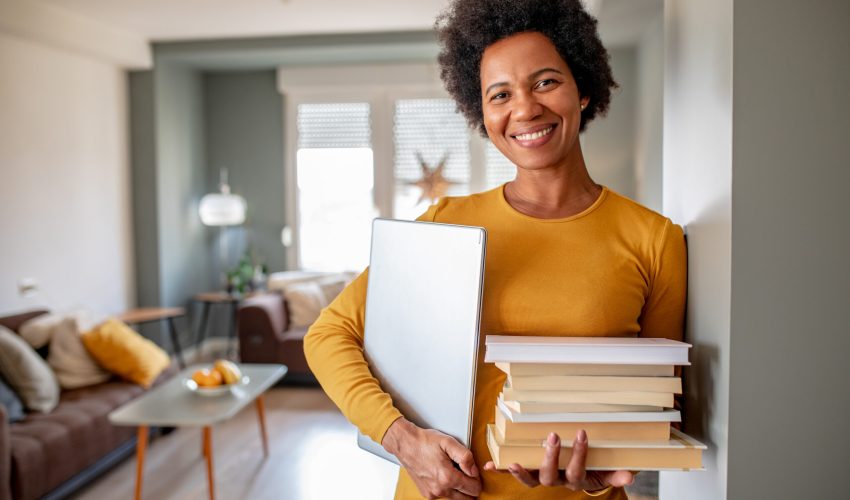 Portrait of woman holding books and laptop